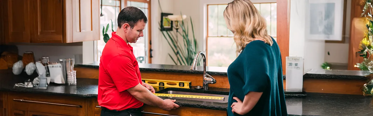 Handyman measuring a kitchen sink for a customer