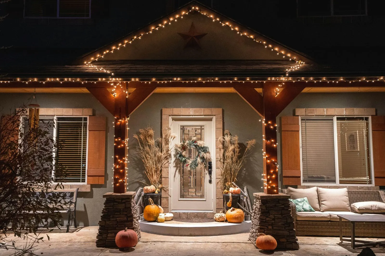 Warm white string lights outlining the gable, eaves and porch posts of a house at night