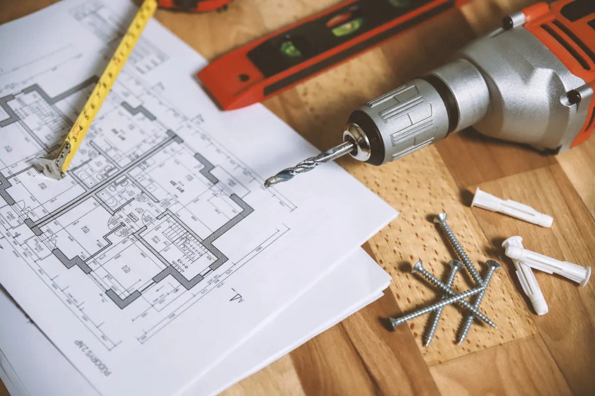 Drill, level and wall anchors laid out on a floor plan