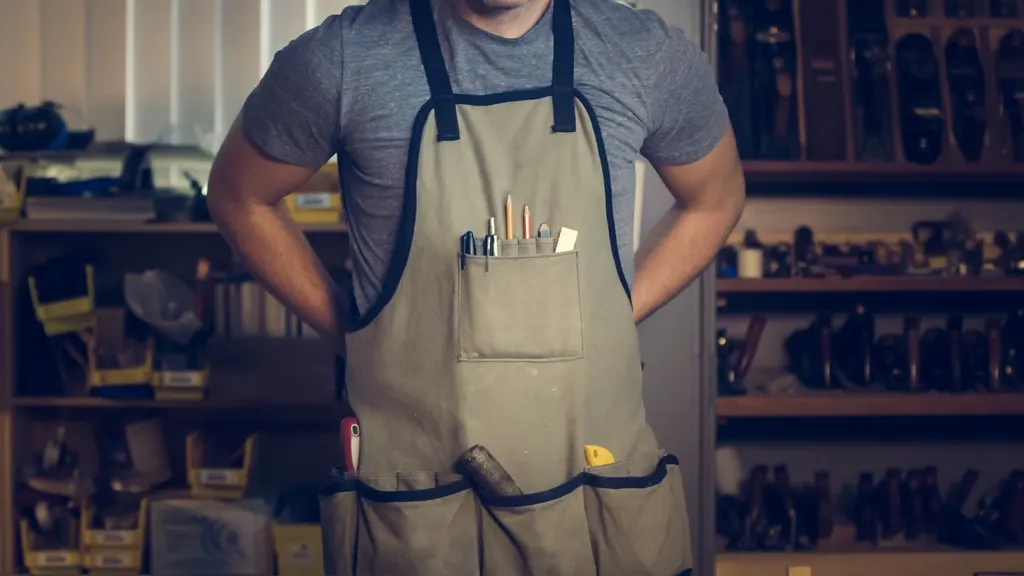 Handyman in a canvas tool apron in a workshop