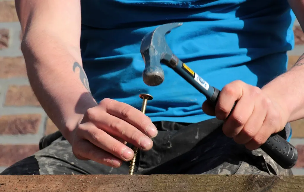Handyman driving a nail into a wooden board