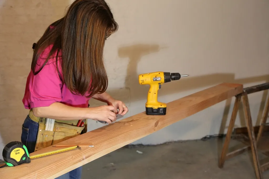 Handywoman measuring a wooden board next to a cordless drill