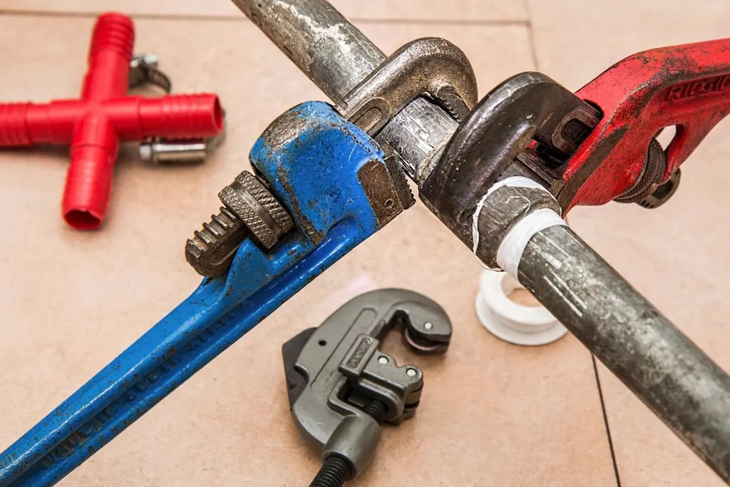 Pipe wrenches tightening a fitting on a water pipe